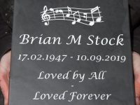 Slate memorial tablet with musical theme.