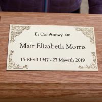 Deep engraved black letters with scratch engraved decoration on brass plaque.